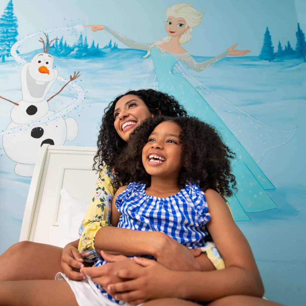 Mother and daughter sitting together in a bedroom themed to Disney’s Frozen at Encore Resort