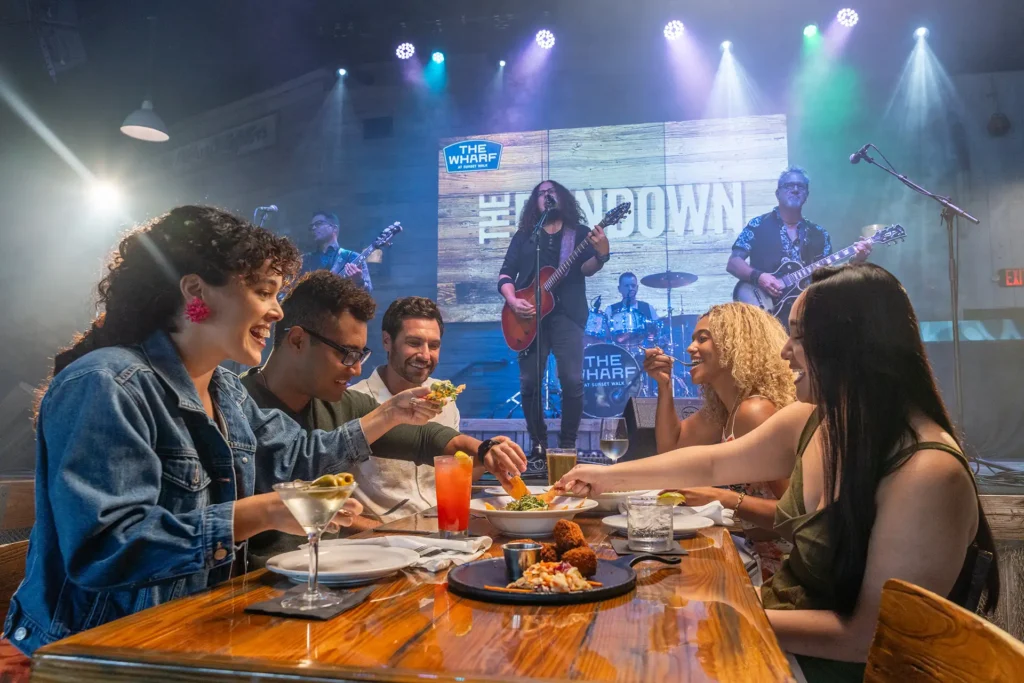 Group dining at The Wharf at Sunset Walk in front of a live band on stage