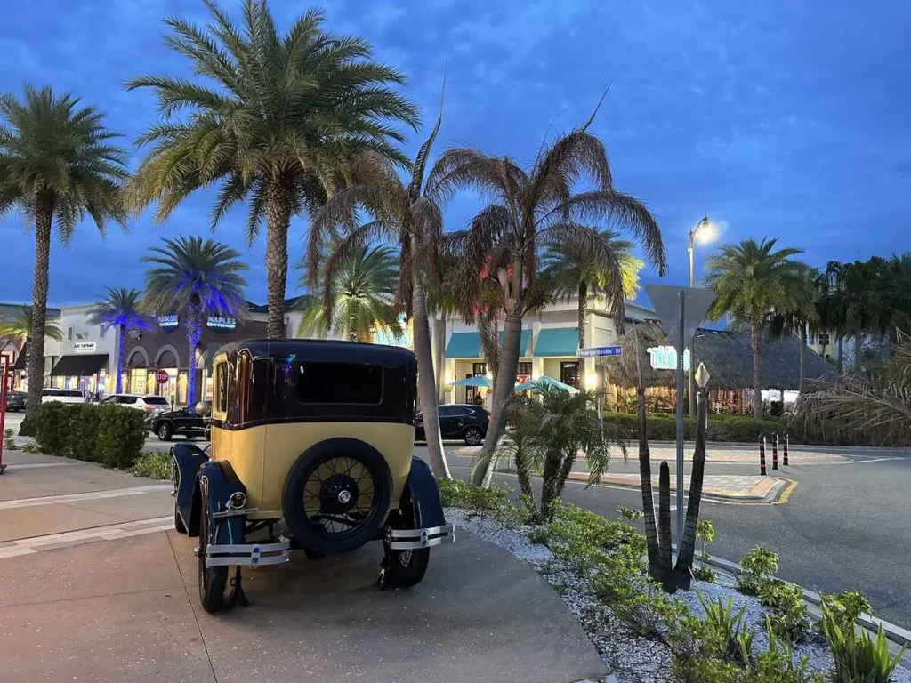 Vintage car parked near palm trees and illuminated shops at Margaritaville Resort Orlando in the evening. (Photo: Helen Hatzis/Trip Jaunt)