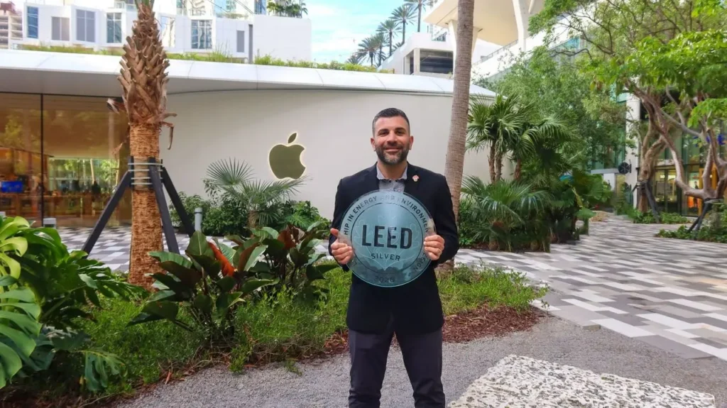 Matt Falcone holding a LEED-ND Certification silver plaque outside at Miami Worldcenter